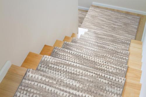The design of staircase inside the house are paved with light brown wood laminate.